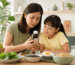 Parent and child comparing a liquid children's multivitamin with iron alongside balanced foods